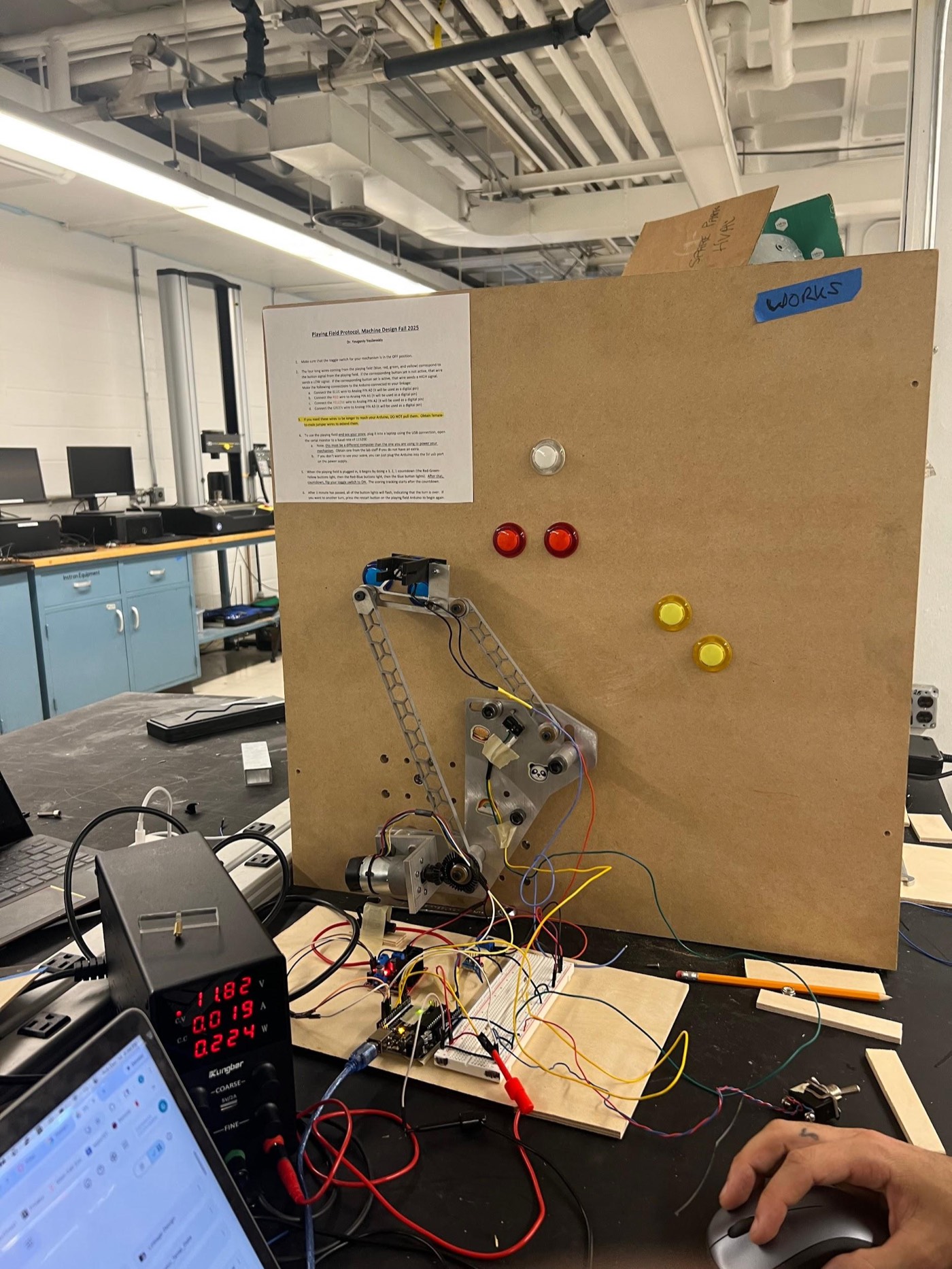 The full test setup: linkage mounted on the wall board, wired to the electronics stack on the bench below.